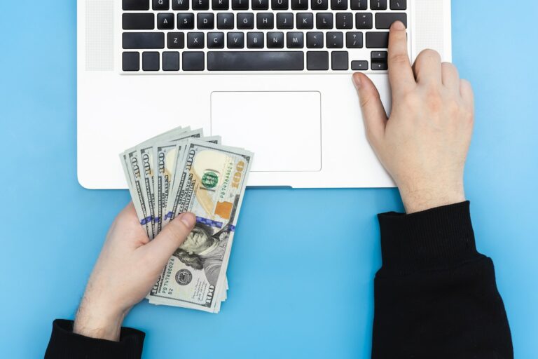 Laptop and money in male hands, top view.